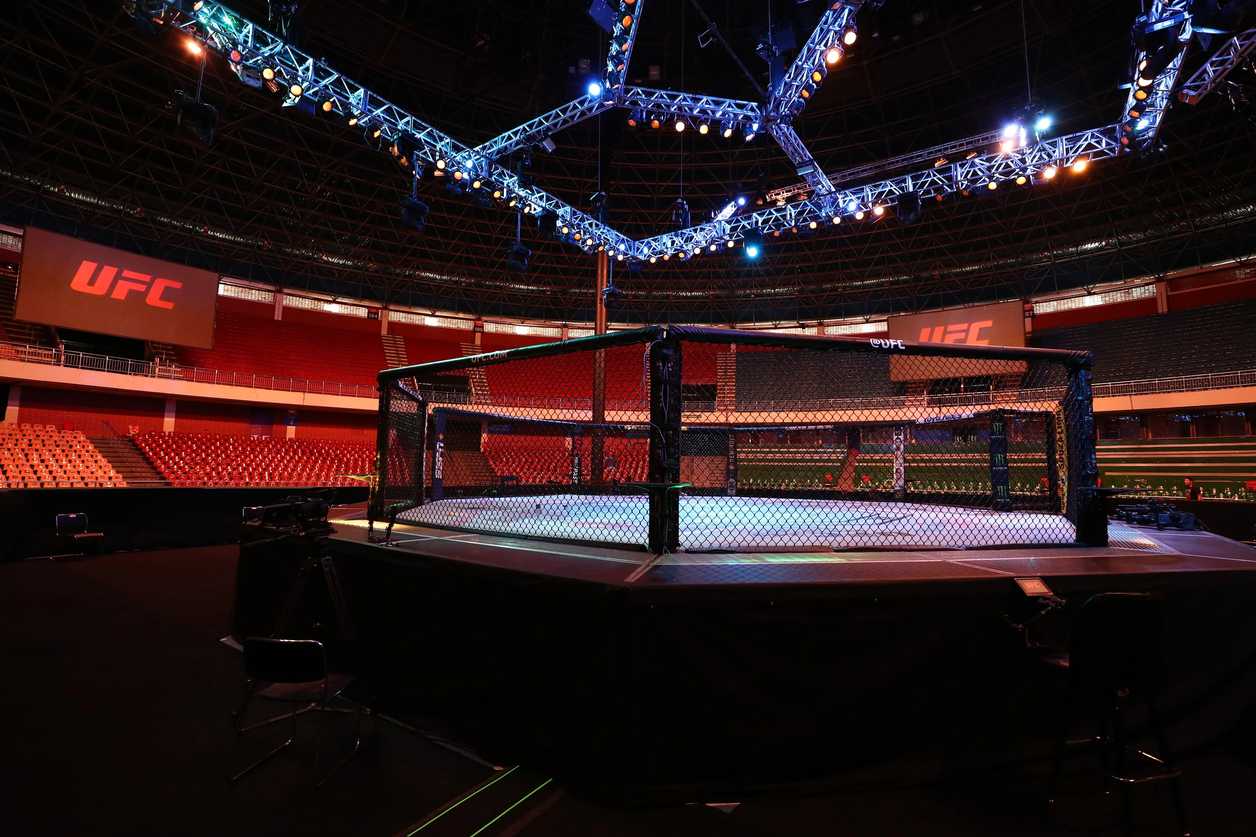 The UFC Octagon under blue and orange arena lights